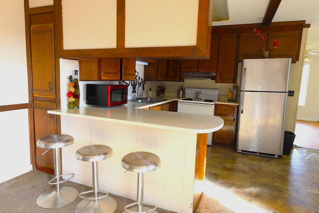 kitchen with a breakfast bar, sink, electric range, kitchen peninsula, and stainless steel refrigerator