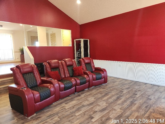 cinema room featuring hardwood / wood-style floors and vaulted ceiling