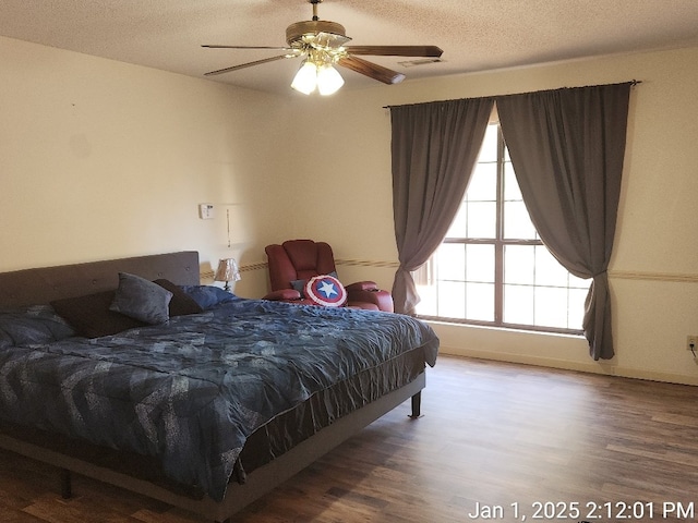 bedroom featuring ceiling fan, wood-type flooring, and a textured ceiling