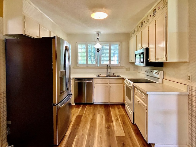 103 Peartree Cir, Dothan, AL 36301 - kitchen with stainless steel appliances, a sink, light wood-type flooring, light countertops, and white cabinetry