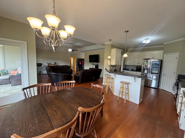 dining space with ornamental molding, dark wood-type flooring, and ceiling fan with notable chandelier