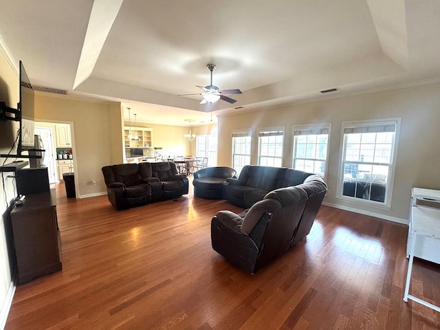 living room with dark wood-style floors, a raised ceiling, visible vents, and baseboards