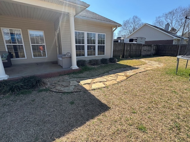 view of yard with a trampoline, fence, and a patio