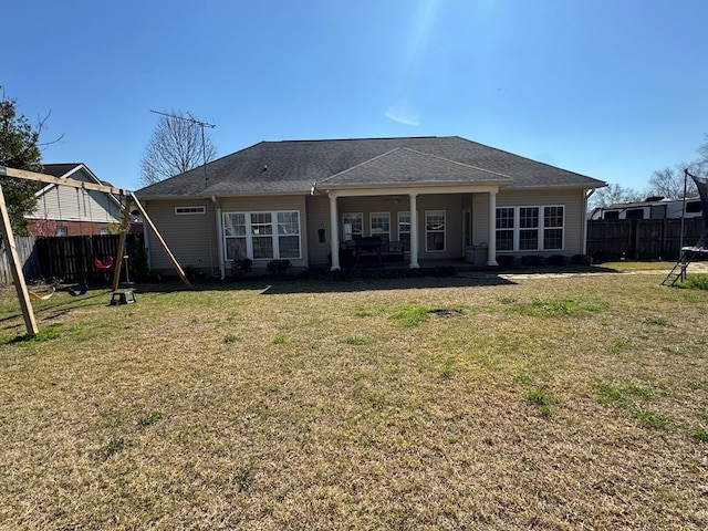 rear view of house with a lawn and fence