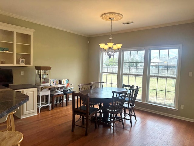 dining area featuring crown molding, dark wood-style flooring, plenty of natural light, and an inviting chandelier