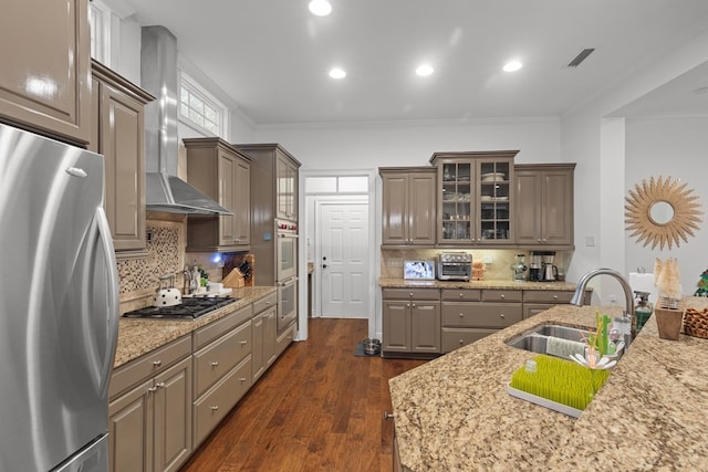 kitchen with dark wood-type flooring, wall chimney range hood, sink, ornamental molding, and stainless steel appliances