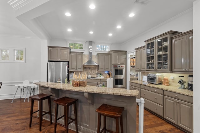 kitchen featuring stainless steel appliances, a kitchen island, dark wood-type flooring, and wall chimney range hood