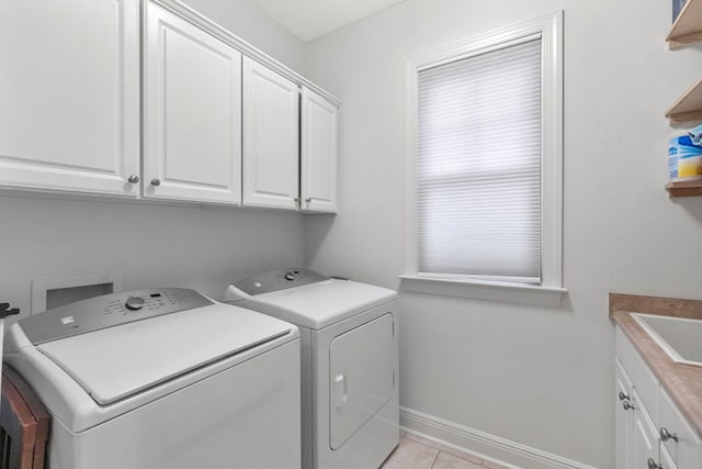 washroom featuring washer and dryer, cabinets, and light tile patterned flooring