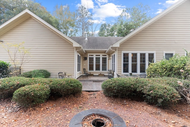 rear view of property with a patio and a fire pit