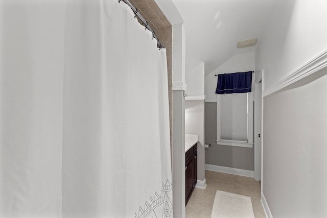 bathroom featuring tile patterned flooring, vanity, and lofted ceiling