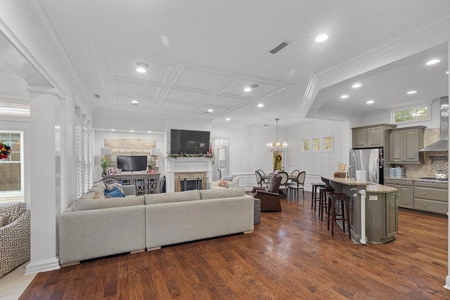 living room with crown molding, dark wood-type flooring, and an inviting chandelier