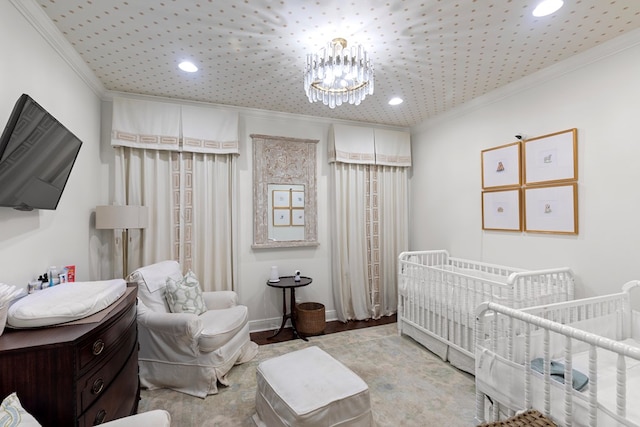 bedroom featuring an inviting chandelier, light hardwood / wood-style flooring, a nursery area, and ornamental molding