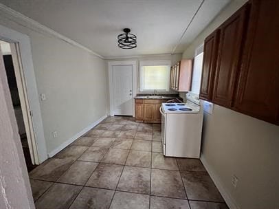 laundry area featuring cabinets, light tile patterned floors, and crown molding