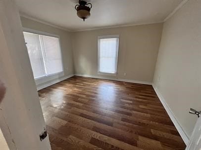 empty room with dark hardwood / wood-style flooring and crown molding