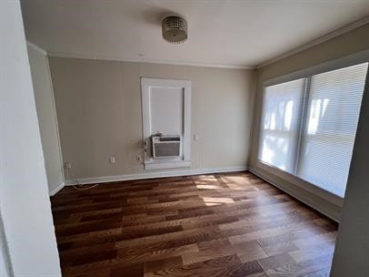 unfurnished room with crown molding, baseboards, cooling unit, and wood finished floors