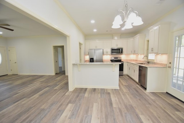 kitchen with white cabinetry, sink, hanging light fixtures, light hardwood / wood-style flooring, and appliances with stainless steel finishes