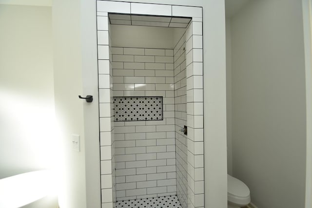 bathroom featuring toilet and tiled shower