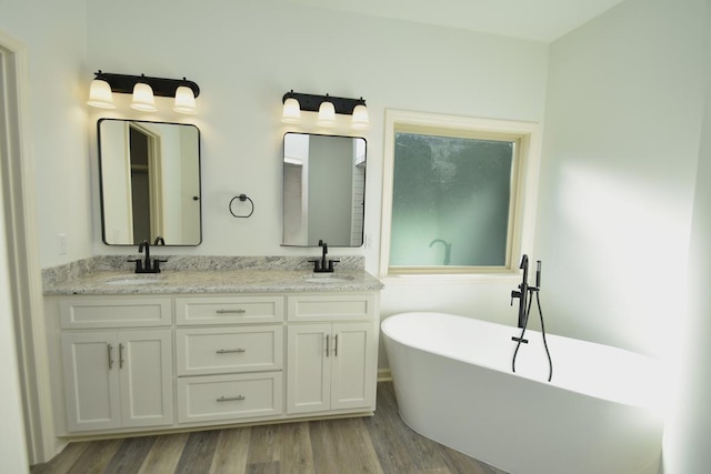 bathroom with wood-type flooring, vanity, and a tub