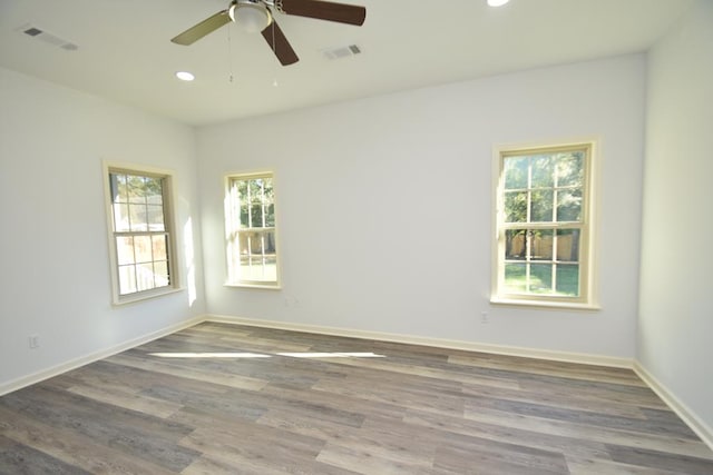 spare room featuring wood-type flooring, a wealth of natural light, and ceiling fan