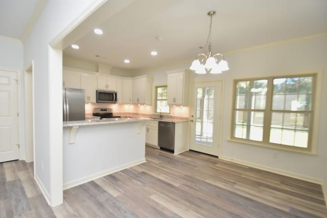 kitchen featuring an inviting chandelier, white cabinets, hanging light fixtures, light hardwood / wood-style floors, and stainless steel appliances