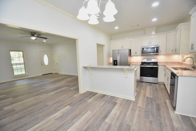 kitchen with stainless steel appliances, white cabinetry, light hardwood / wood-style floors, and sink