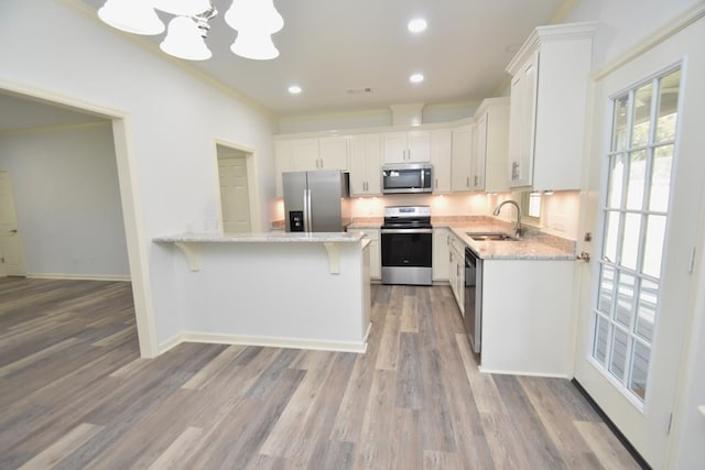 kitchen with sink, stainless steel appliances, light hardwood / wood-style flooring, a chandelier, and white cabinets