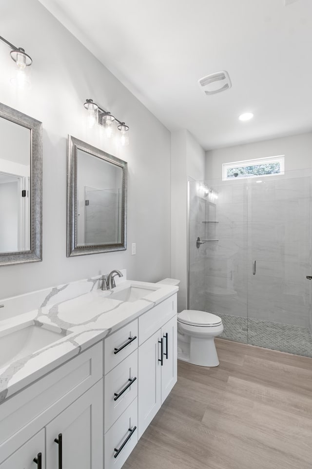 bathroom with vanity, toilet, wood-type flooring, and a shower with door