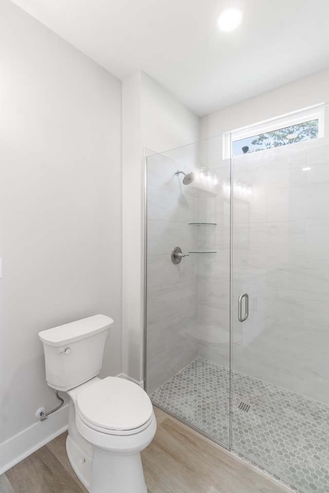 bathroom featuring a shower with shower door, toilet, and wood-type flooring