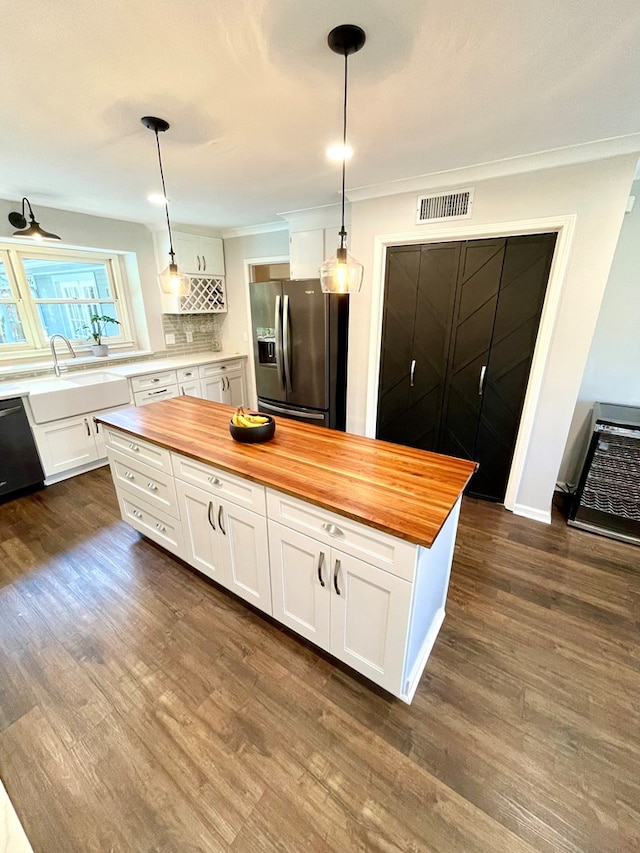 kitchen featuring white cabinets, appliances with stainless steel finishes, decorative light fixtures, and butcher block countertops