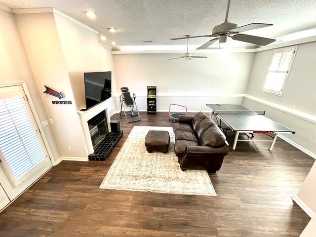 living room with a textured ceiling, a fireplace, ornamental molding, and dark wood-type flooring