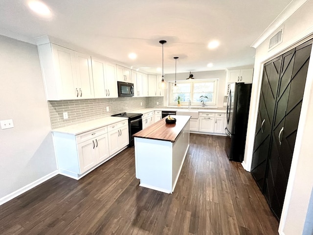 kitchen featuring a kitchen island, butcher block countertops, pendant lighting, white cabinets, and black appliances