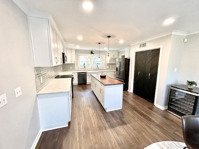 kitchen with white cabinetry, a center island, hanging light fixtures, wood counters, and appliances with stainless steel finishes