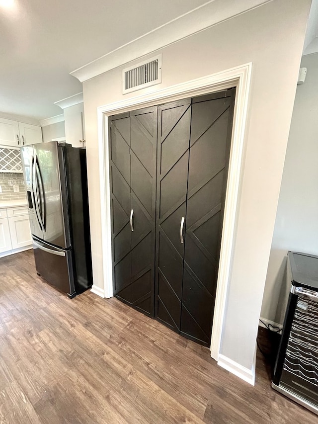 interior space featuring stainless steel fridge, backsplash, light wood-type flooring, heating unit, and white cabinets