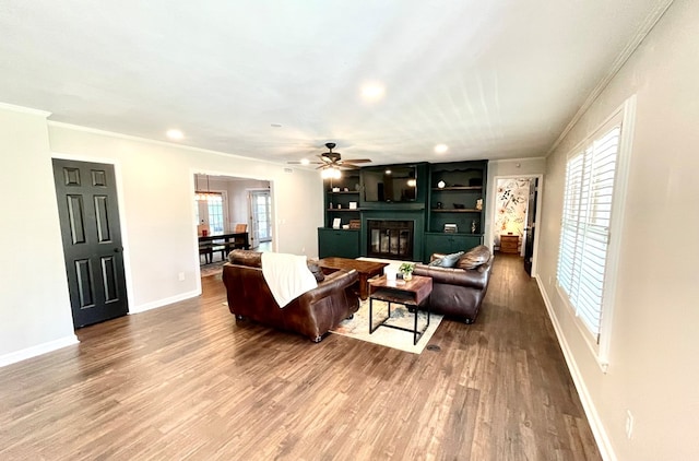 living room featuring hardwood / wood-style flooring, ceiling fan, and crown molding