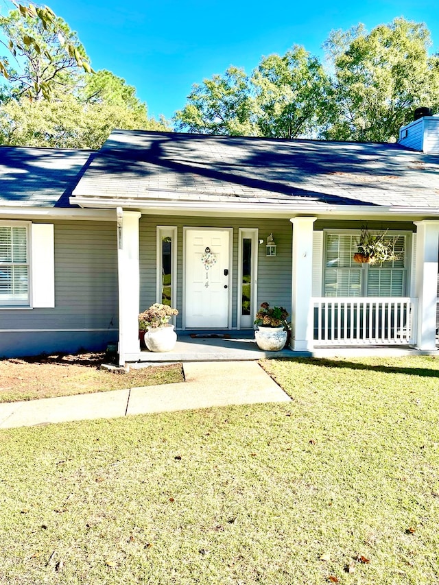 doorway to property featuring a lawn and a porch