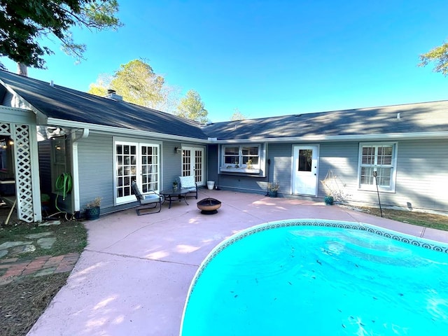 view of swimming pool with french doors, a fire pit, and a patio area