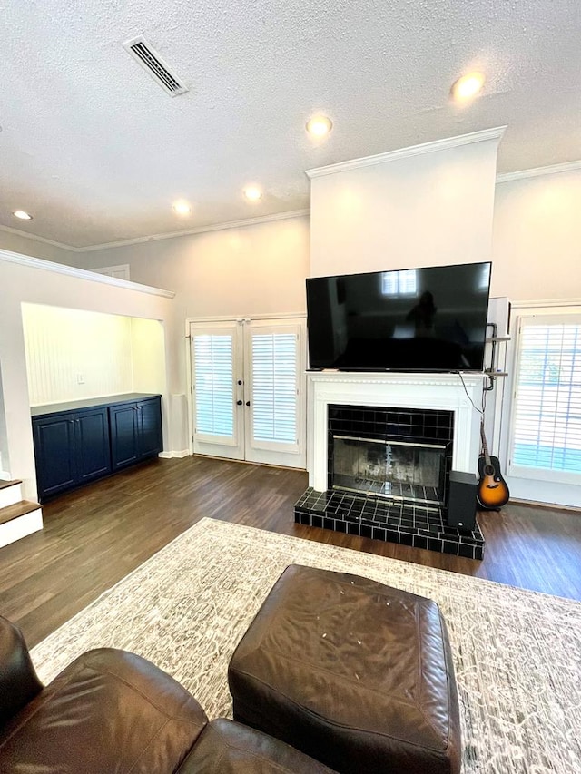 living room with a fireplace, a textured ceiling, dark hardwood / wood-style floors, and crown molding