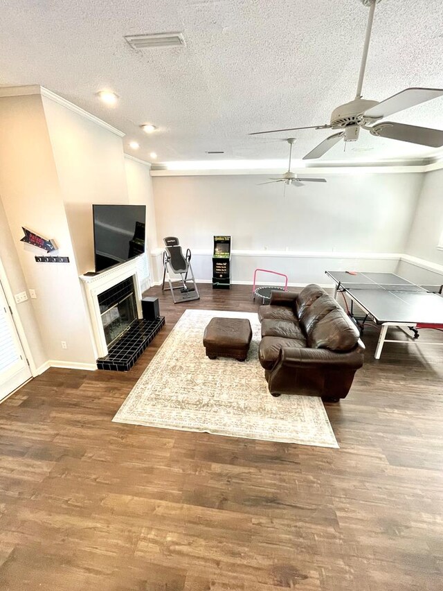 living room featuring wood-type flooring, a textured ceiling, ceiling fan, and crown molding