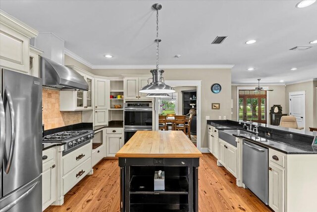 3195 Singletary Rd, Slocomb, AL 36375 - kitchen featuring appliances with stainless steel finishes, wall chimney exhaust hood, butcher block countertops, open shelves, and ornamental molding