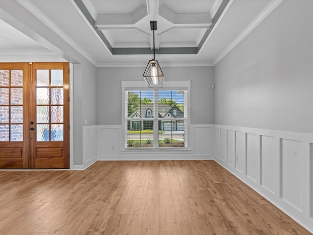 unfurnished dining area featuring light wood finished floors, wainscoting, coffered ceiling, beam ceiling, and a decorative wall