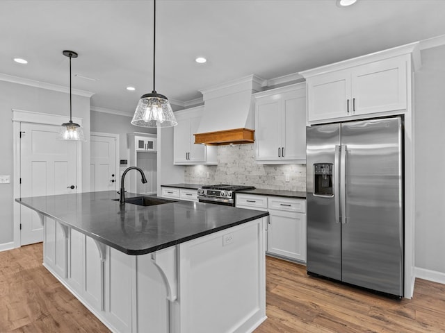kitchen featuring stainless steel appliances, a sink, premium range hood, dark countertops, and white cabinets
