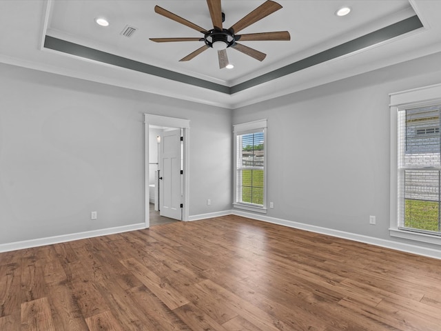 spare room featuring a raised ceiling, ceiling fan, wood finished floors, crown molding, and recessed lighting
