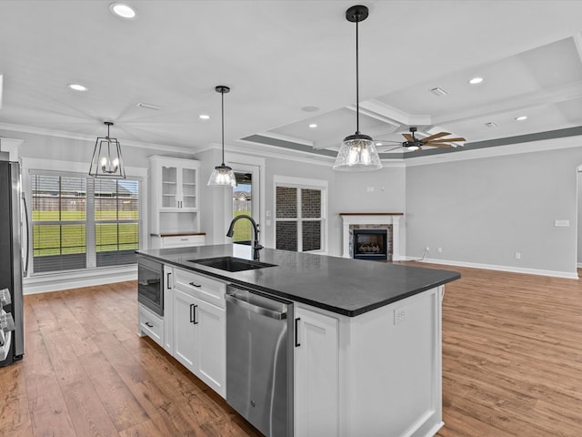 kitchen featuring a sink, appliances with stainless steel finishes, dark countertops, crown molding, and a fireplace