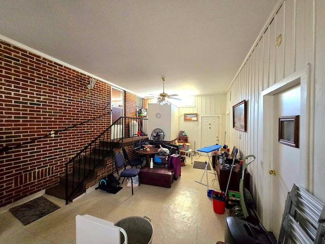 living room with ceiling fan, brick wall, wood walls, and ornamental molding