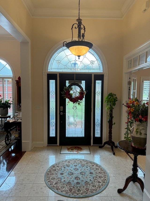 tiled foyer with crown molding and a healthy amount of sunlight