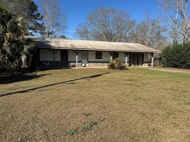 ranch-style home with stone siding, metal roof, a front lawn, and a carport