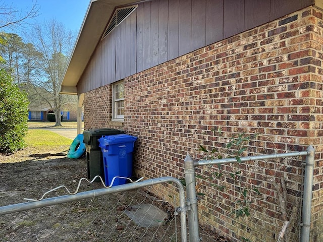 view of property exterior with brick siding and fence