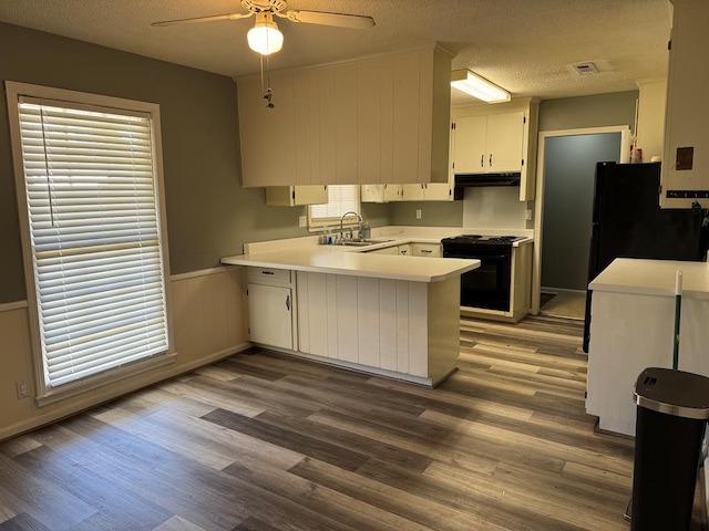 kitchen featuring gas range oven, light countertops, white cabinetry, a sink, and a peninsula