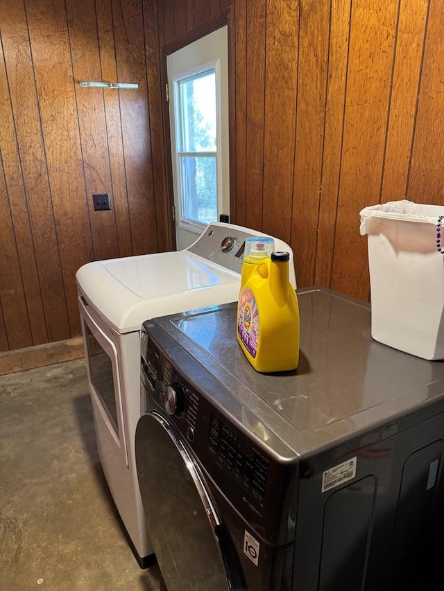 washroom featuring laundry area, wood walls, and washing machine and clothes dryer