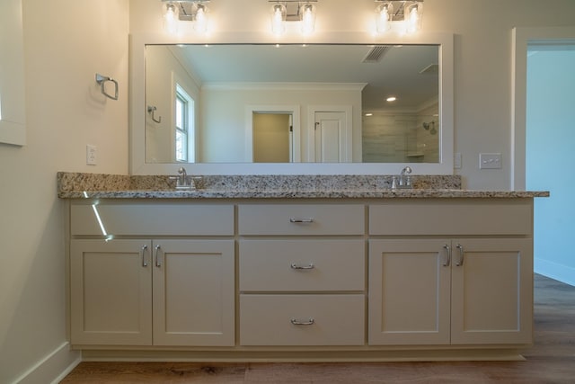 full bath featuring double vanity, a tile shower, visible vents, and baseboards